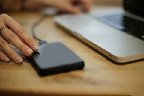 Hand plugging an external hard drive into a laptop to check recognition Hand plugging an external hard drive into a laptop to check recognition