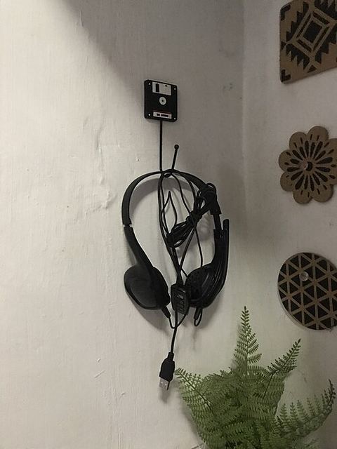 Plantronics USB headset hanging on a wall hook near a workspace Plantronics USB headset hanging on a wall hook near a workspace