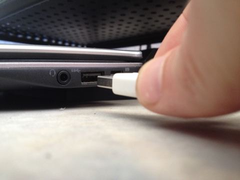 Person plugging a USB device into a laptop port Person plugging a USB device into a laptop port