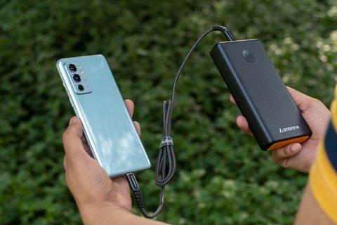 Man charging a smartphone outdoors with a portable power bank Man charging a smartphone outdoors with a portable power bank