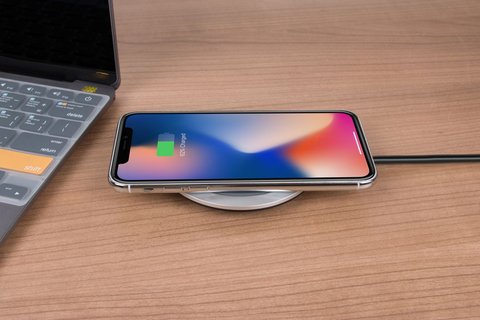 Close up of a smartphone charging wirelessly on a desk Close up of a smartphone charging wirelessly on a desk