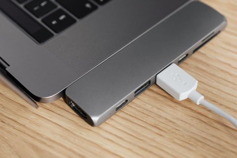 Laptop connected to peripheral device on wooden desk during setup Laptop connected to peripheral device on wooden desk during setup