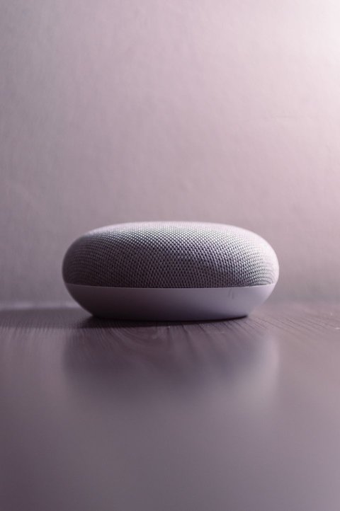 Compact smart speaker on wooden surface with soft ambient lighting background Compact smart speaker on wooden surface with soft ambient lighting background