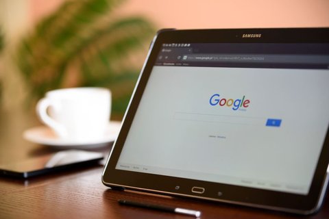 Samsung branded tablet propped on a wooden desk showing a browser search page Samsung branded tablet propped on a wooden desk showing a browser search page
