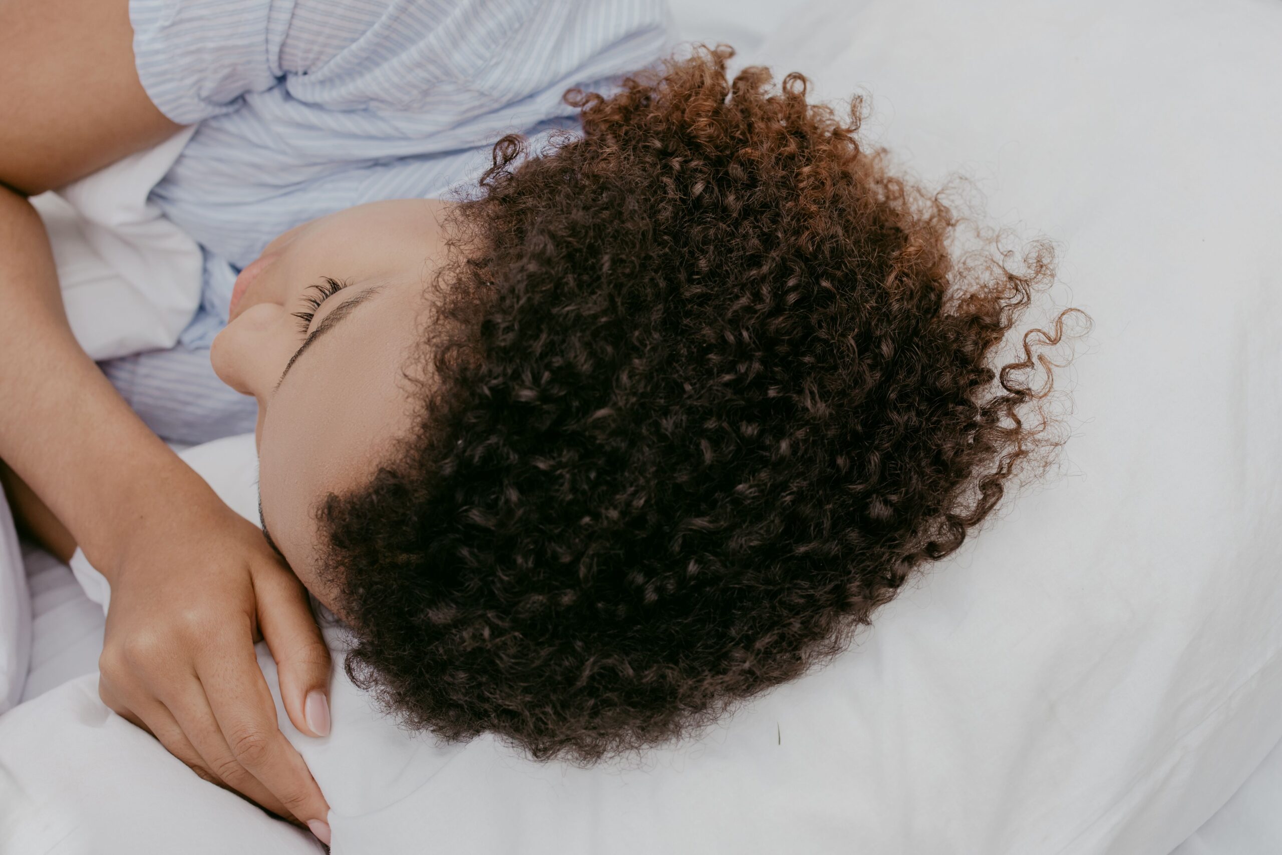 Side sleeper resting comfortably on a pillow while wearing small wireless earbuds Side sleeper resting comfortably on a pillow while wearing small wireless earbuds