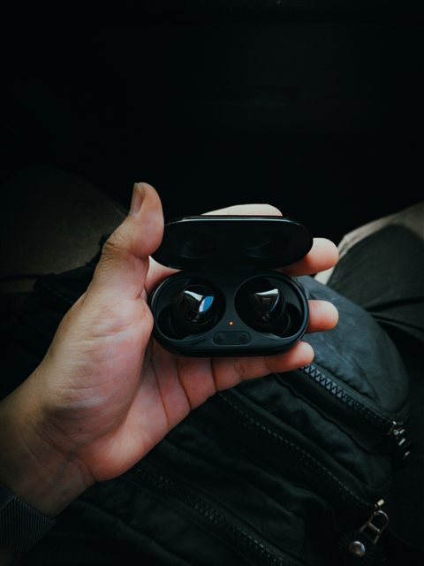 Hand holding an open black earbud charging case with both buds inside Hand holding an open black earbud charging case with both buds inside