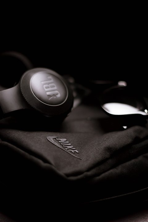 Wireless over-ear headphones resting on a wooden desk surface Wireless over-ear headphones resting on a wooden desk surface