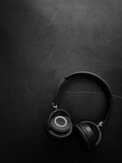 Wireless headphones with soft ear cushions resting on a wooden tabletop Wireless headphones with soft ear cushions resting on a wooden tabletop