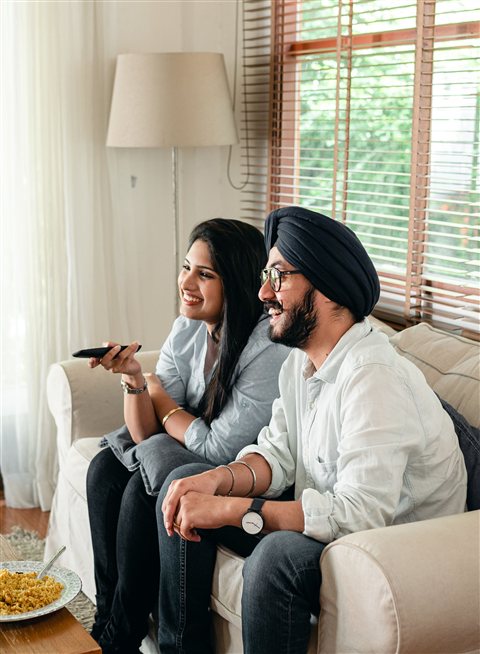People relaxing together in a living room in the evening with a television on People relaxing together in a living room in the evening with a television on