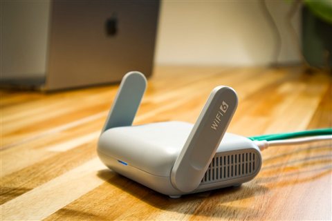 Modern WiFi 6 router placed on a wooden desk during home network setup Modern WiFi 6 router placed on a wooden desk during home network setup