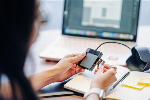 Inserting an SD memory card into a card reader at a work desk