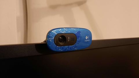Compact webcam resting on top of a monitor bezel