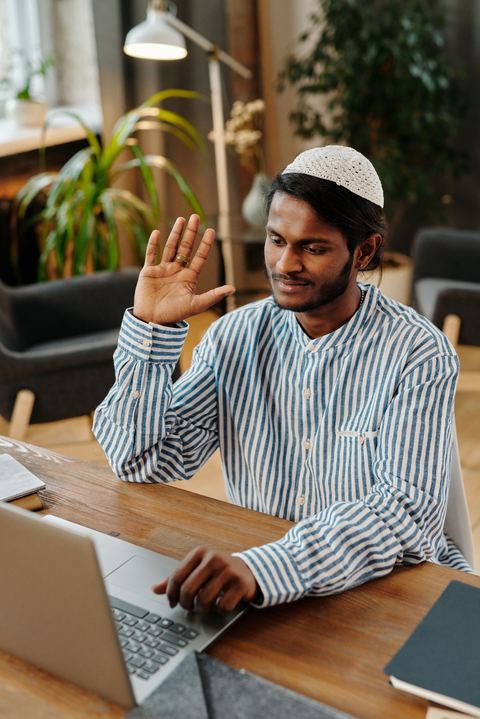 Man waving at the camera during a webcam video call Man waving at the camera during a webcam video call