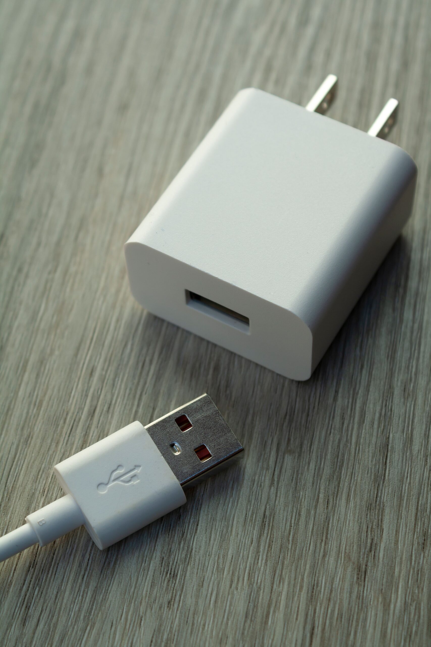 Close-up of USB charger and cable on wood surface