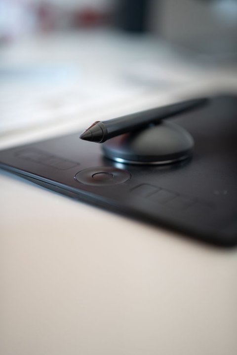 Macro shot of a black tablet pen tip resting on the surface of a drawing tablet