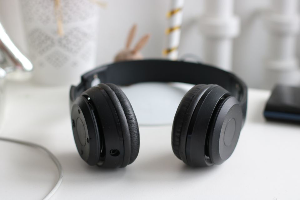Black wireless headphones on a desk Black wireless headphones on a desk