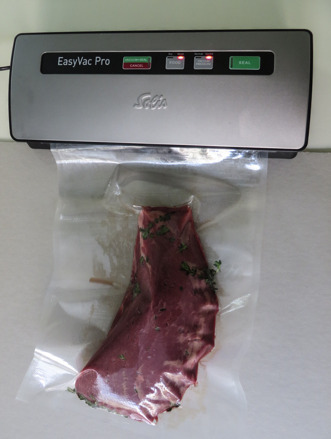 Vacuum-sealed food bag prepared for sous vide cooking alongside an immersion circulator Vacuum-sealed food bag prepared for sous vide cooking alongside an immersion circulator
