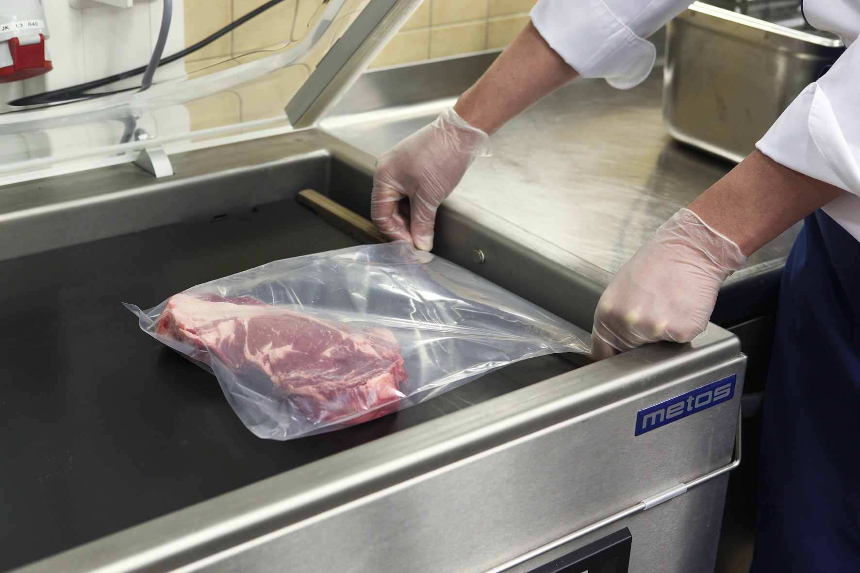Vacuum sealing machine preparing a steak for sous vide cooking in a commercial kitchen Vacuum sealing machine preparing a steak for sous vide cooking in a commercial kitchen