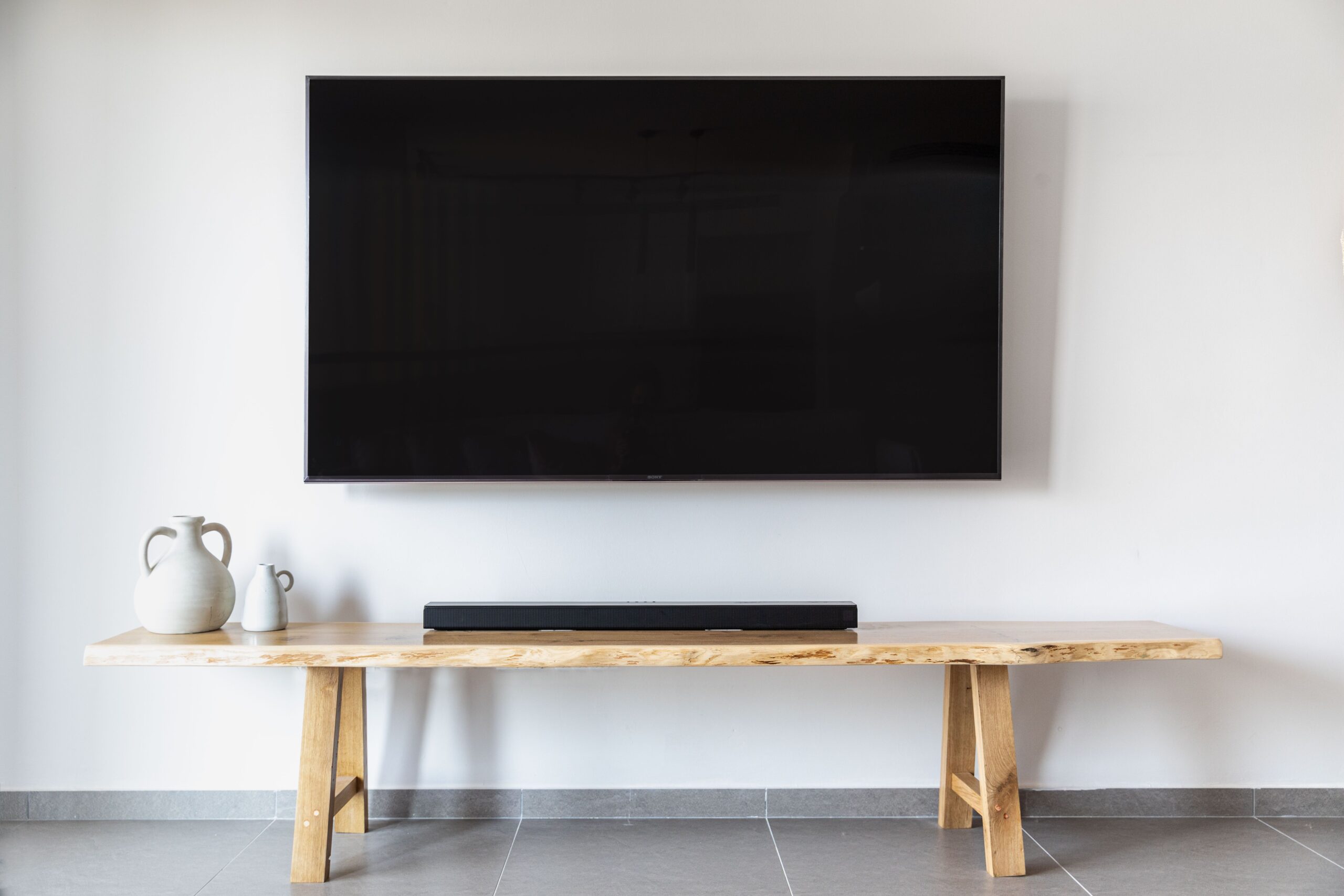 Soundbar and subwoofer placed below a wall mounted television in a living room Soundbar and subwoofer placed below a wall mounted television in a living room