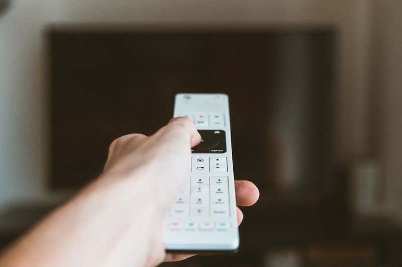 Hand holding remote control pointed at TV during soundbar software update