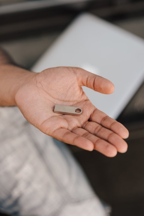 USB drive resting in a hand next to a laptop used for firmware updates USB drive resting in a hand next to a laptop used for firmware updates