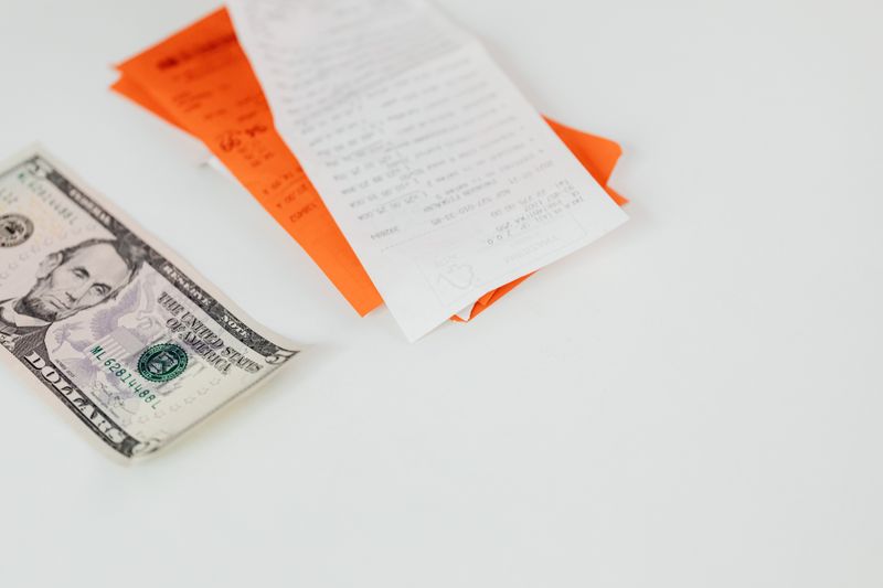 Printed cash register receipt next to paper currency on a counter Printed cash register receipt next to paper currency on a counter