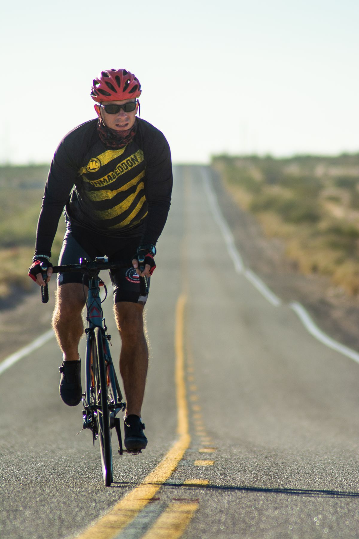 Cyclist riding along a long open road during a long distance training session Cyclist riding along a long open road during a long distance training session