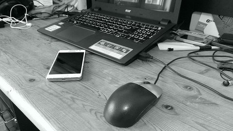 Corded computer mouse and phone on a wooden desk with laptop nearby Corded computer mouse and phone on a wooden desk with laptop nearby