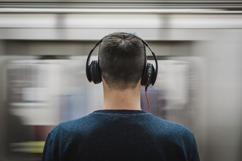 Person wearing wireless headphones on the go while music streams from a connected phone Person wearing wireless headphones on the go while music streams from a connected phone
