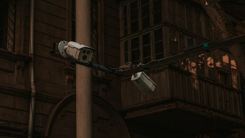 Security camera mounted on a pole overlooking a residential building at dusk